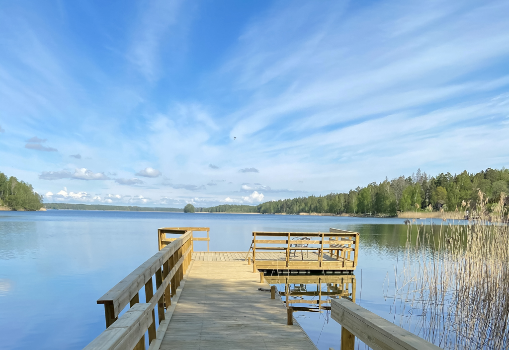 Träbrygga som leder ut mot en sjö under en klarblå himmel