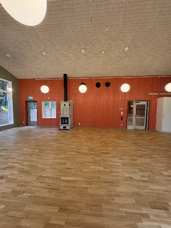 Det nya aktivitetsrummet med träklädda väggar, kamin och ljust trägolv.