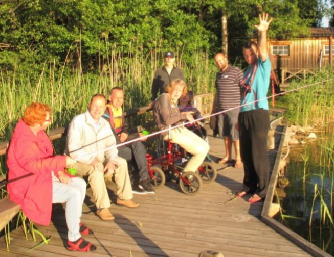 En grupp sitter på bryggan och fiskar.